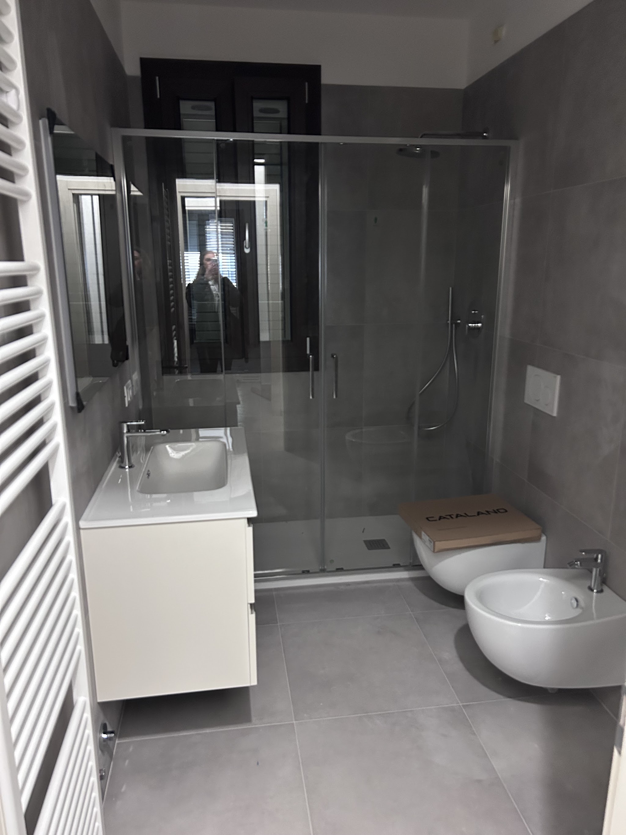 Bagno rinnovato con doccia e rivestimenti grigi